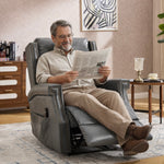 Man relaxing in LL1260 gray leather recliner chair while reading, showcasing comfort and ergonomic design in a cozy living room.